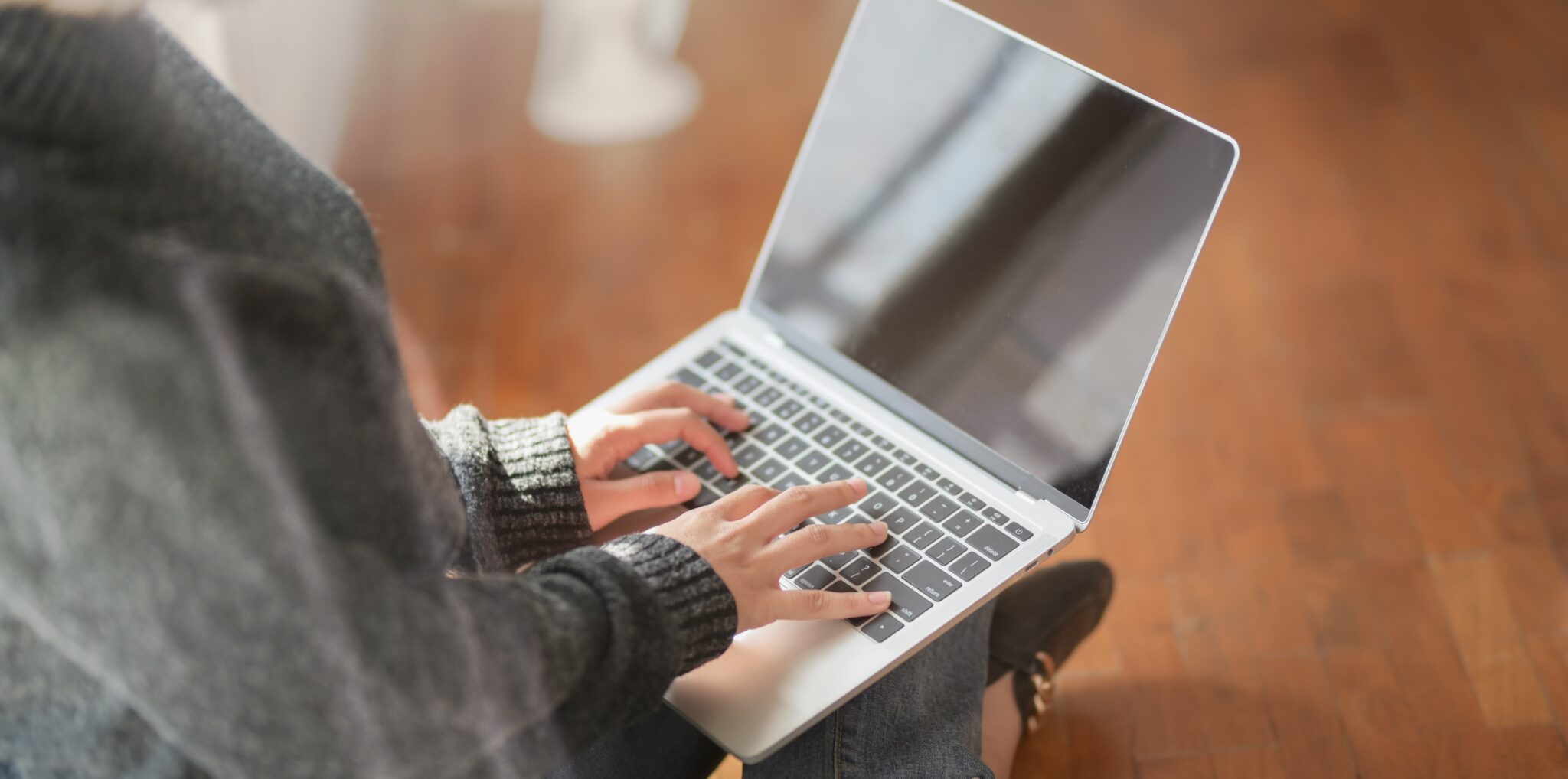 Transcreation, as the name implies, is more creative than normal translation. Description: A woman with a grey jumper typing on a MacBook laptop while sitting on the floor.