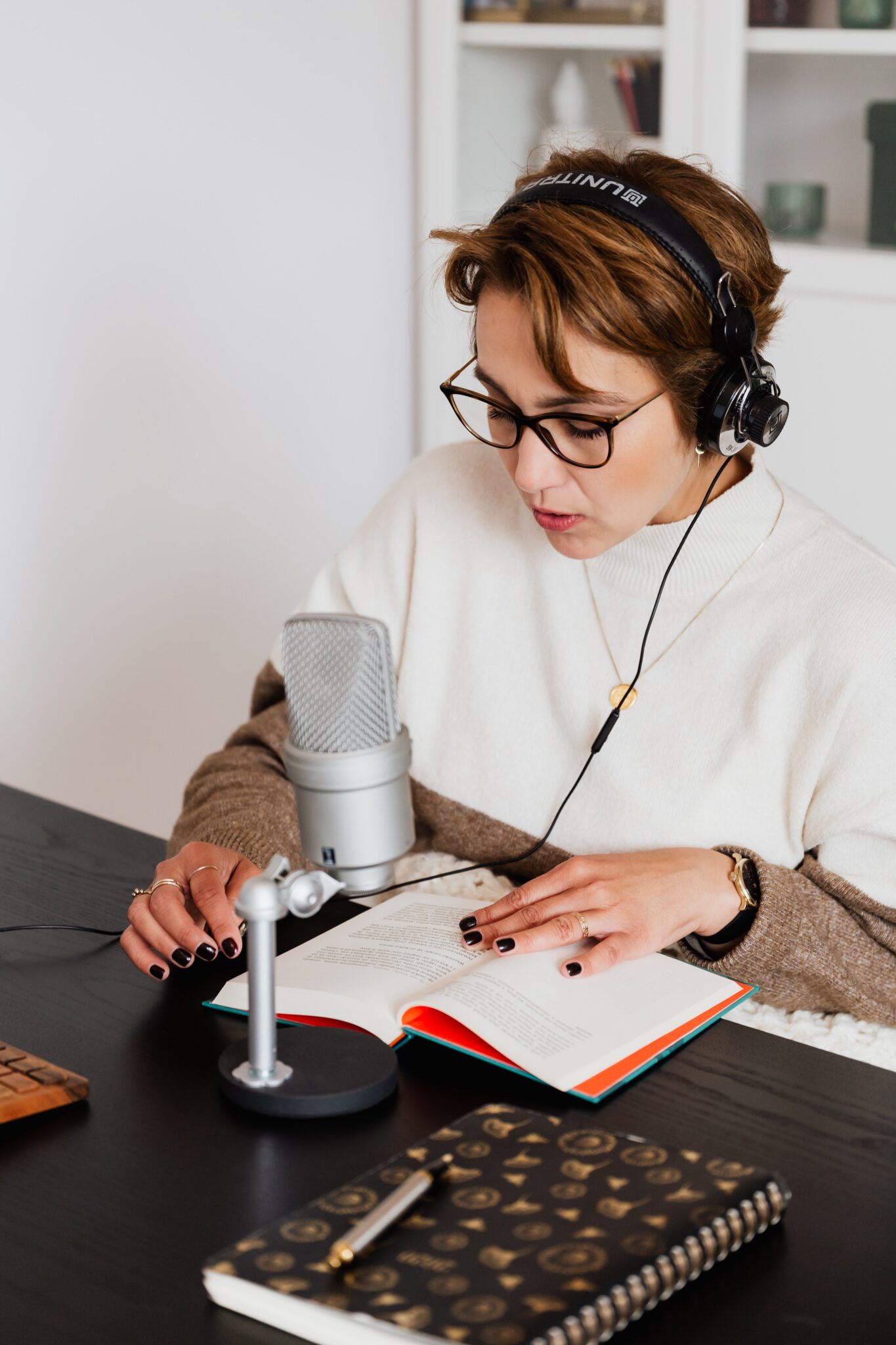 Interpretation requires a lot of concentration on the interpreters part, and usually a quiet room to focus in.

A person is sitting at a desk and speaking in front of a microphone, reading from a book, with headphones on.